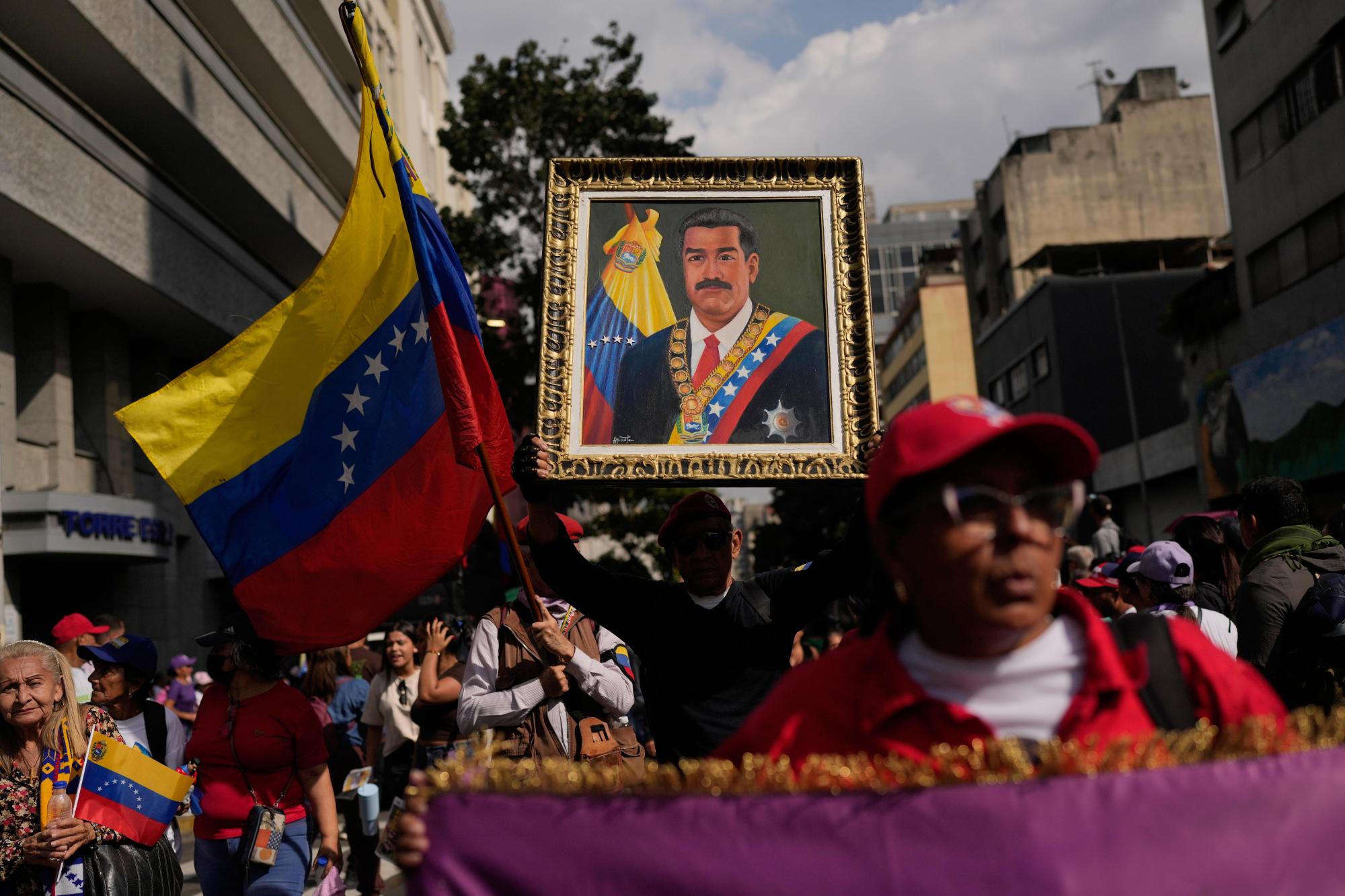 A government supporter holds an image of President Nicolas Maduro during a women’s march to demand his return in Caracas, Venezuela, Tuesday, Jan. 6, 2026, three days after U.S. forces captured him and his wife. (AP Photo/Matias Delacroix)
